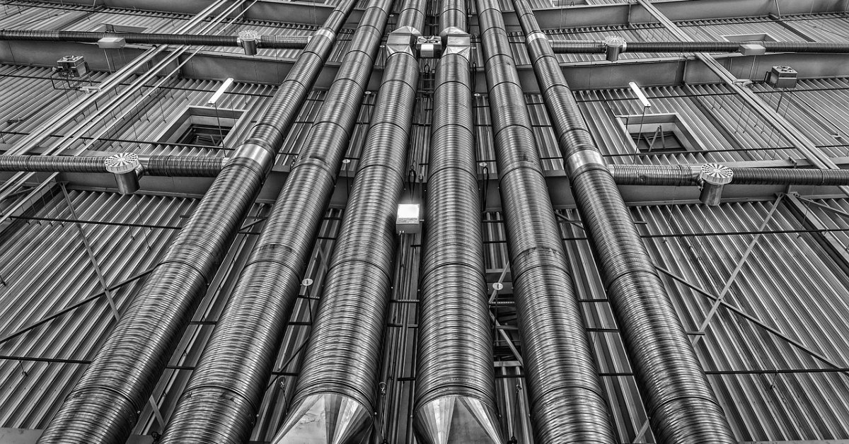 Zwart-witbeeld van grote leidingen tegen een industriële gevel